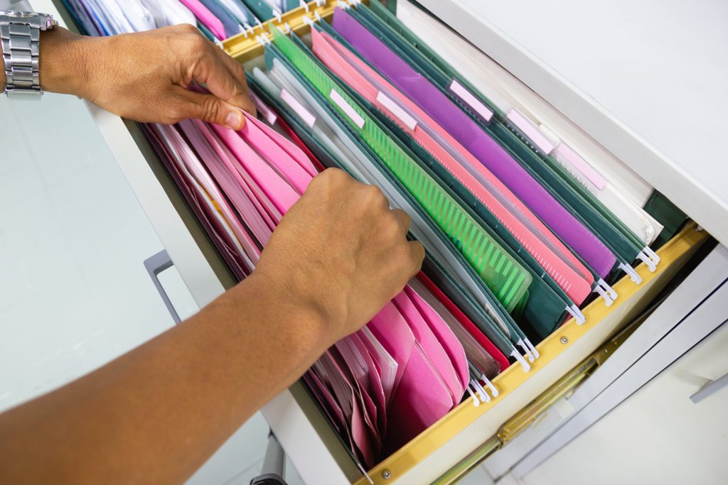 Man hands Search files document of hanging file folders in drawer in a whole pile of full papers, concept