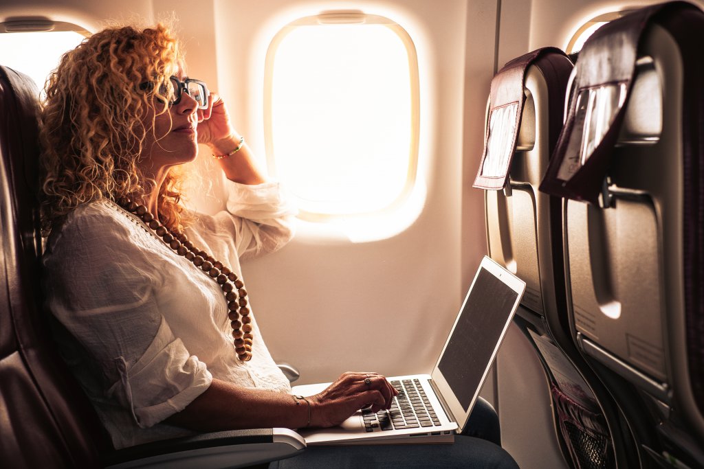 Business adult beautiful curly blonde woman travel on airplane c