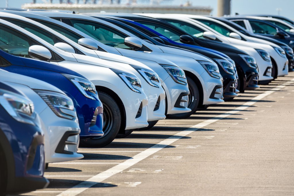 Row of brand new cars lined up outdoors in a parking lot.