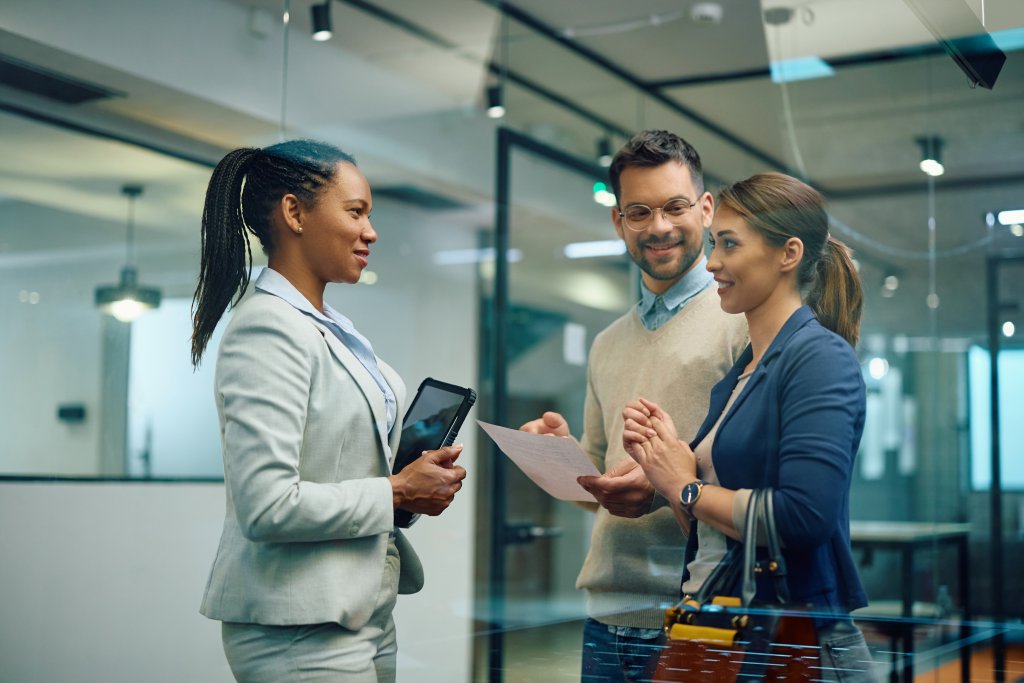 Young happy couple communicating with female real estate agent in office.