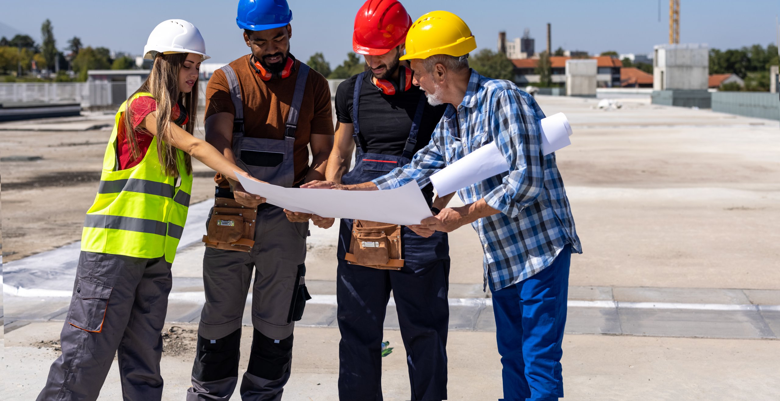 Senior Construction Engineer is Holding a Paper Plans and Doing Analysis with his Younger Coworkers.