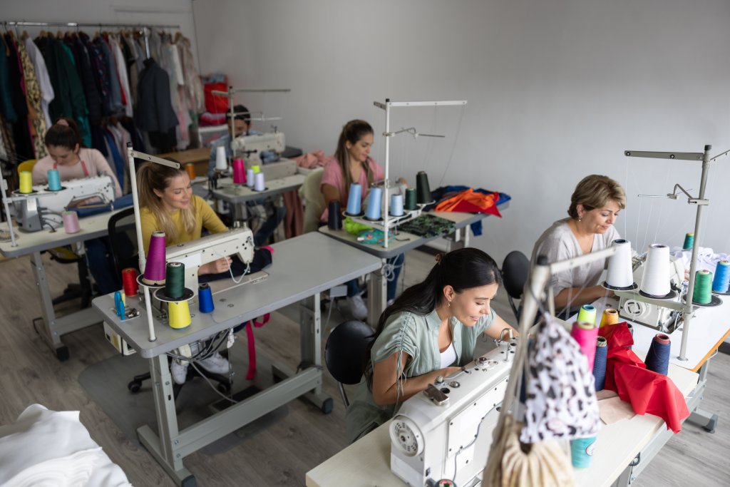 Group of seamstresses sewing clothes at an atelier using sewing machines