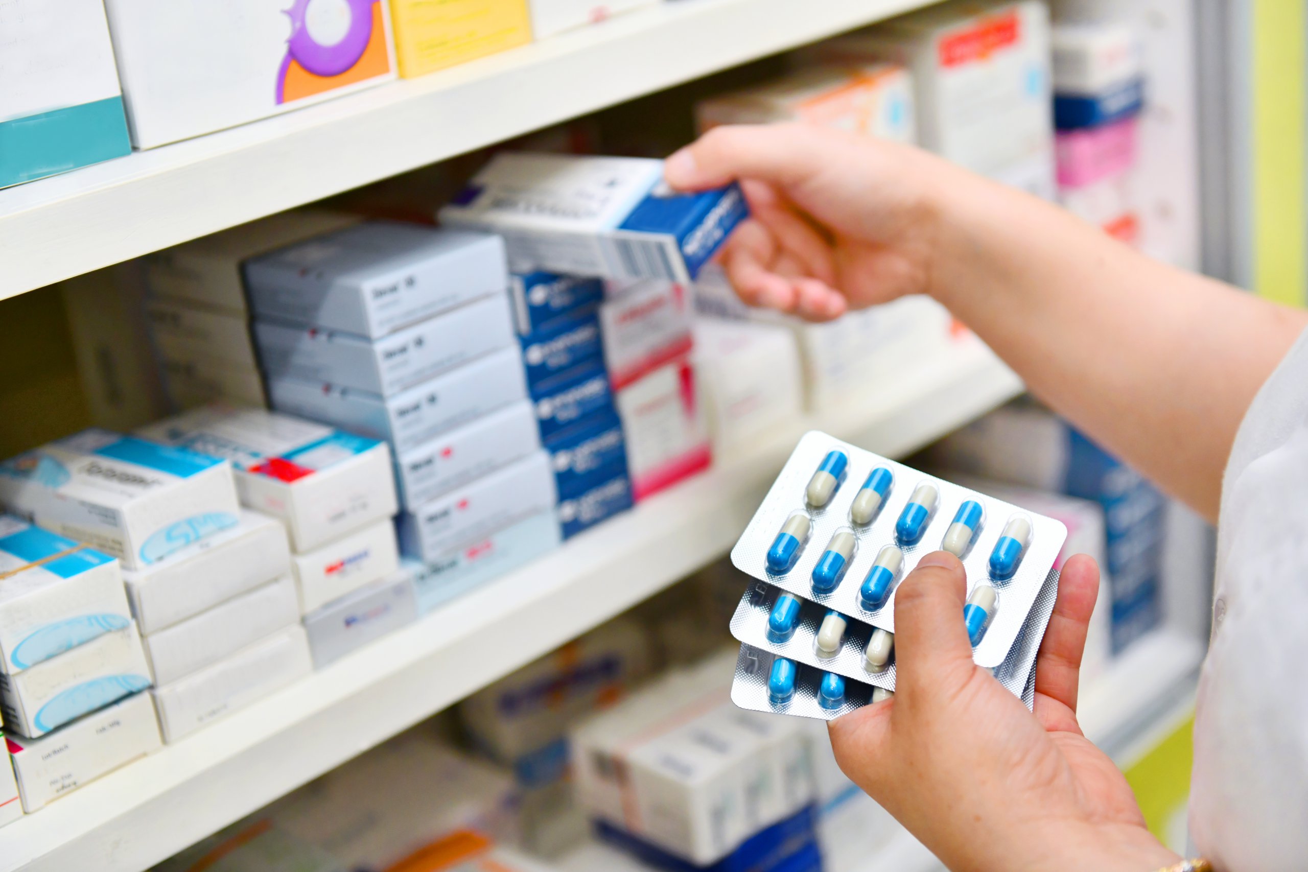 Pharmacist holding medicine box and capsule pack in pharmacy dru